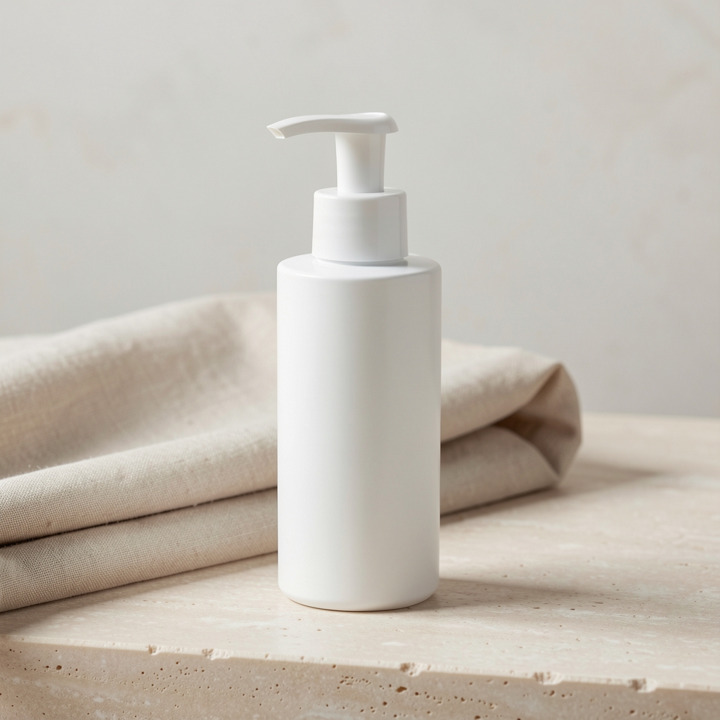 White pump-bottle of body lotion placed on a pale stone surface beside a folded linen cloth, clean minimal studio photography